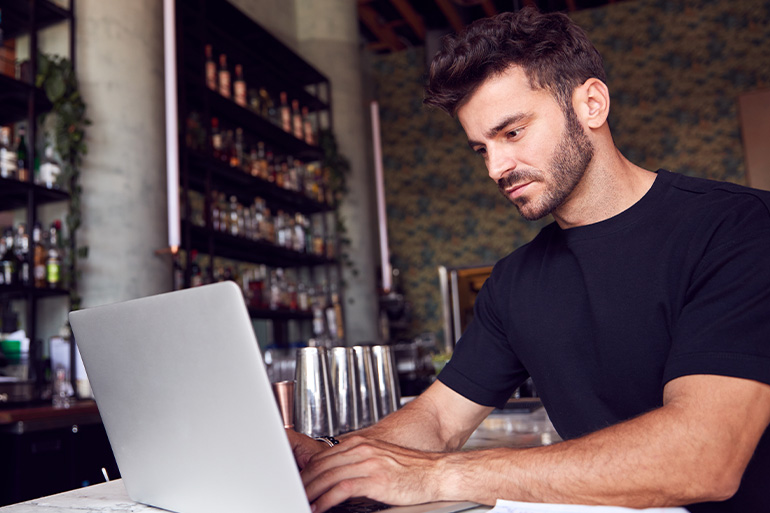 Person sat at a laptop searching Google in a restaurant