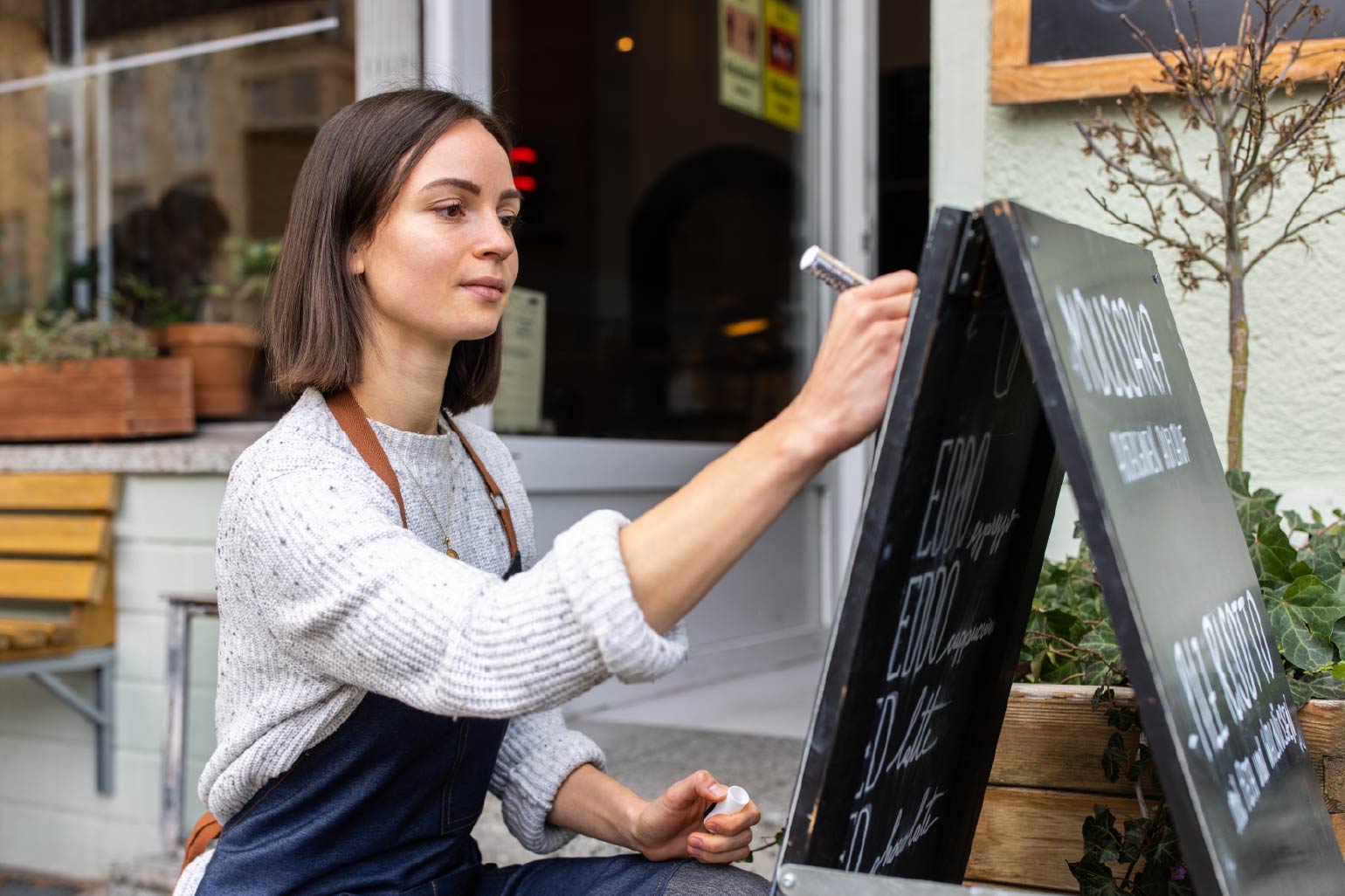 A woman updating the menu outside of a restaurant. 