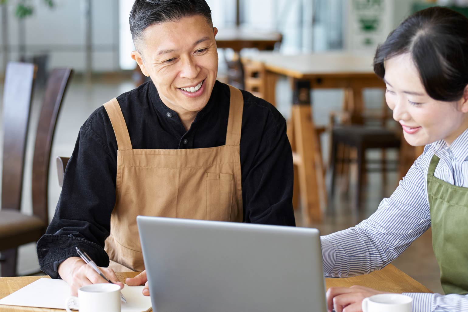 A man and woman sitting in a restaurant looking at a computer screen. 