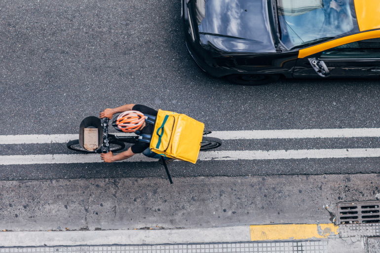 A food delivery worker on a bicycle in the street.